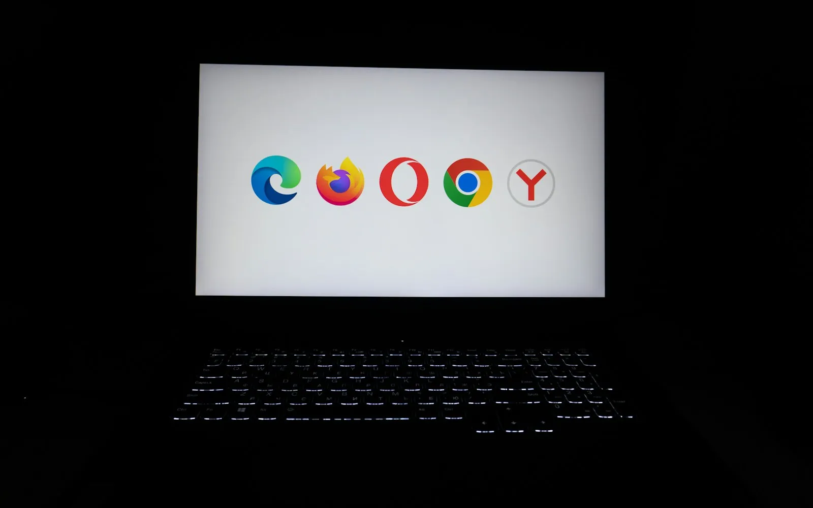 Laptop screen in a dark room showing the logos of several popular web browsers