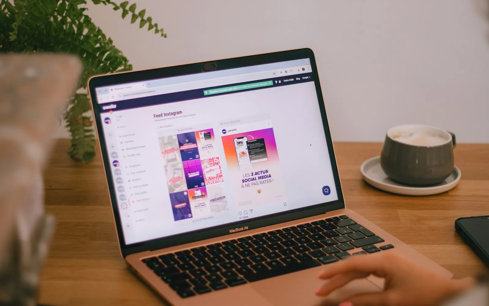 Laptop on a wooden desk showing a busy web page next to a cup of coffee